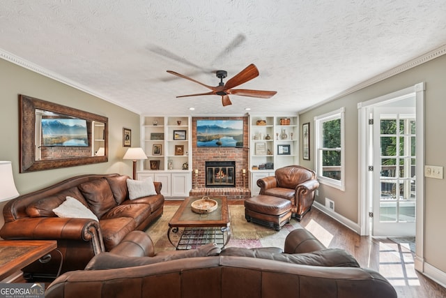 10875 Shagbark Trl, Roswell, GA 30075 - living room featuring ceiling fan, wood finished floors, a fireplace, crown molding, and built in features