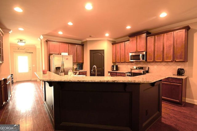 560 Tuscany Walk Ln, Lawrenceville, GA 30043 - kitchen with stainless steel appliances, a large island, crown molding, dark wood finished floors, and light stone countertops