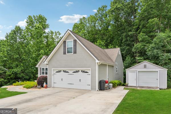 5102 Yellow Stone Dr, Flowery Branch, GA 30542 - view of front of house featuring a garage, an outdoor structure, a front yard, and driveway