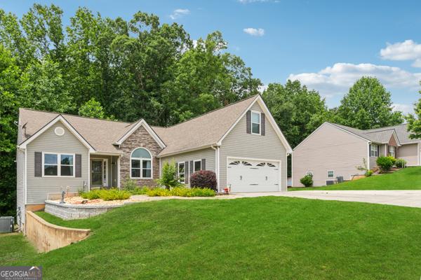 5102 Yellow Stone Dr, Flowery Branch, GA 30542 - view of front of property with concrete driveway, a front lawn, stone siding, cooling unit, and a garage