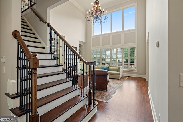 4530 Westgate Dr, Cumming, GA 30040 - stairway featuring healthy amount of natural light, wood finished floors, a high ceiling, a chandelier, and crown molding