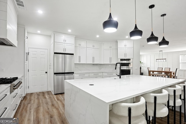 194 Branch Valley Way, Dallas, GA 30132 - kitchen with stainless steel appliances, light wood finished floors, white cabinets, a kitchen breakfast bar, and light stone counters