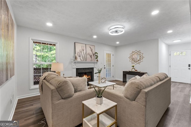 9404 Cypress Ln, Jonesboro, GA 30238 - living room featuring a textured ceiling, a warm lit fireplace, recessed lighting, dark wood-style floors, and baseboards