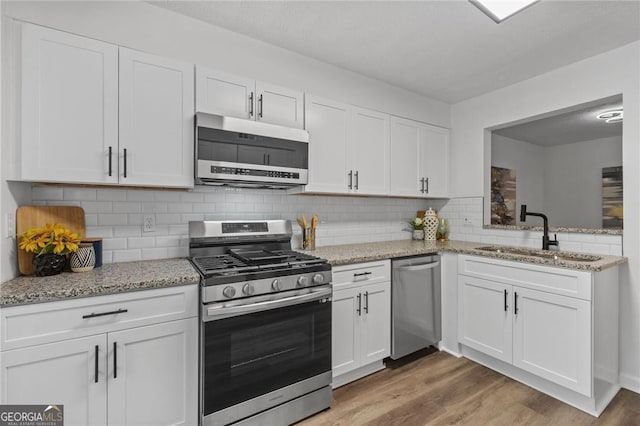 9404 Cypress Ln, Jonesboro, GA 30238 - kitchen with stainless steel appliances, a sink, white cabinetry, light wood-style floors, and light stone countertops