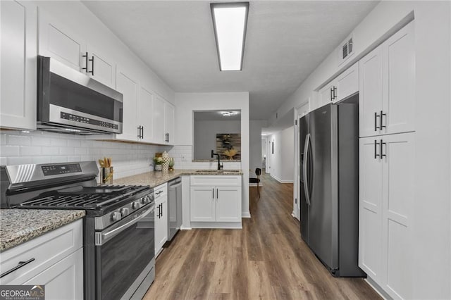 9404 Cypress Ln, Jonesboro, GA 30238 - kitchen featuring stainless steel appliances, a sink, white cabinets, and wood finished floors