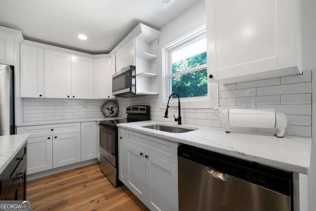 6 W Point Dr SE, Lindale, GA 30147 - kitchen featuring appliances with stainless steel finishes, white cabinetry, light stone countertops, backsplash, and light wood finished floors