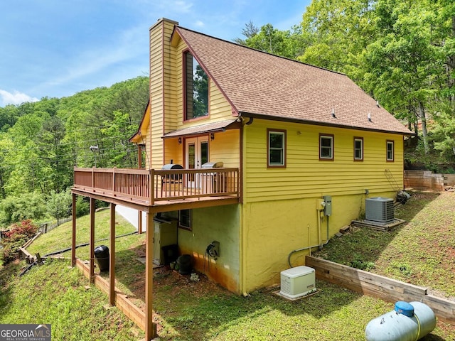 224 Shake Rag Rd, Hiawassee, GA 30546 - back of property featuring central AC, a wooden deck, a chimney, a lawn, and a wooded view