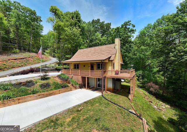 224 Shake Rag Rd, Hiawassee, GA 30546 - rear view of house featuring a wooden deck, a chimney, stairs, a view of trees, and a lawn