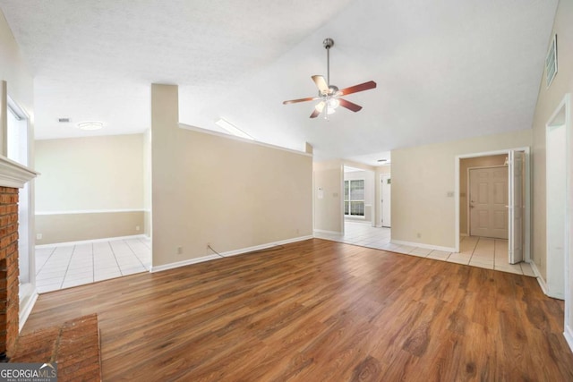 467 Ravinia Way, Lawrenceville, GA 30044 - unfurnished living room featuring a ceiling fan, wood finished floors, vaulted ceiling, a fireplace, and baseboards
