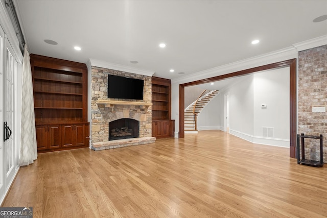 3057 Watsons Bnd, Milton, GA 30004 - unfurnished living room with a fireplace, ornamental molding, light wood finished floors, built in shelves, and stairs