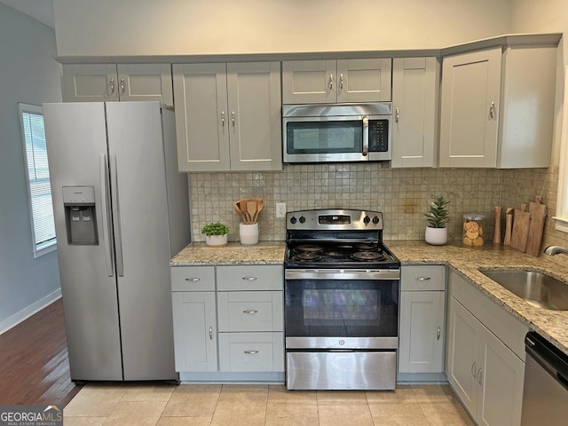 490 Rockwell St SW, Atlanta, GA 30310 - kitchen featuring appliances with stainless steel finishes, gray cabinetry, decorative backsplash, and light stone countertops