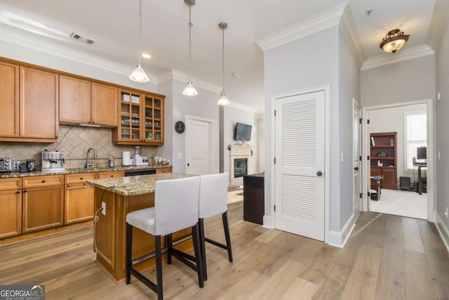 11 Perimeter Ctr E Unit 1412, Atlanta, GA 30346 - kitchen featuring brown cabinets, a breakfast bar area, tasteful backsplash, glass insert cabinets, and light stone counters