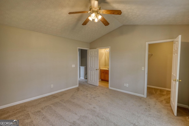 5587 Strathmoor Manor Cir, Lithonia, GA 30058 - unfurnished bedroom with a walk in closet, vaulted ceiling, a textured ceiling, light carpet, and baseboards