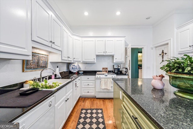 116 Maimont Cir, Macon, GA 31210 - kitchen featuring white gas stove, white cabinetry, light wood finished floors, ornamental molding, and dark stone countertops