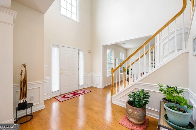 199 Eastham Ct, Suwanee, GA 30024 - entryway featuring stairway, plenty of natural light, a wainscoted wall, wood finished floors, and a towering ceiling