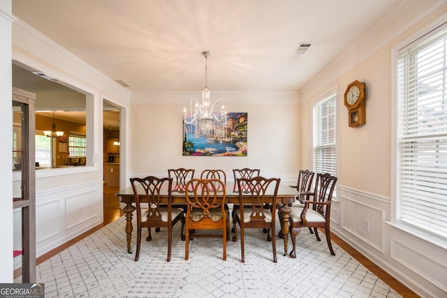 199 Eastham Ct, Suwanee, GA 30024 - dining room featuring a chandelier, a wainscoted wall, light wood-style flooring, a decorative wall, and crown molding