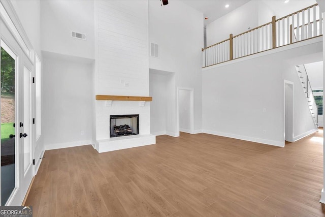 3 Rushden Way SE, Rome, GA 30161 - unfurnished living room featuring a towering ceiling, a brick fireplace, stairway, wood finished floors, and recessed lighting