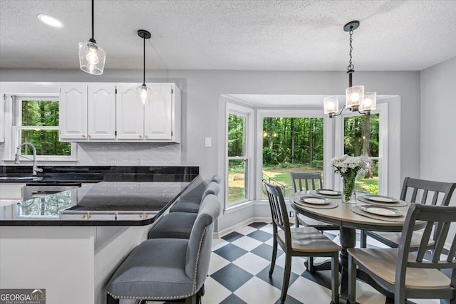 6121 Peake Rd, Macon, GA 31220 - kitchen featuring tile patterned floors, dark countertops, white cabinetry, a chandelier, and a textured ceiling