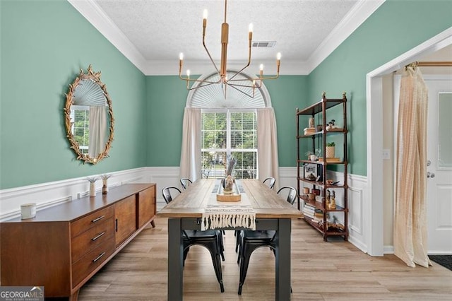 1865 Morgans Run Trl, Buford, GA 30519 - dining area featuring a chandelier, a textured ceiling, a wainscoted wall, light wood-style flooring, and crown molding