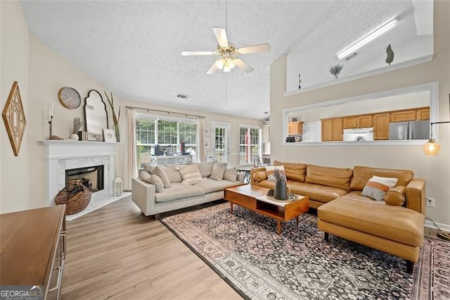1865 Morgans Run Trl, Buford, GA 30519 - living area featuring a textured ceiling, light wood-style flooring, a ceiling fan, a high end fireplace, and high vaulted ceiling