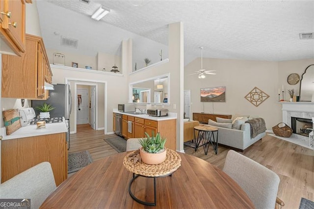 1865 Morgans Run Trl, Buford, GA 30519 - dining space with ceiling fan, light wood-type flooring, a textured ceiling, a high end fireplace, and high vaulted ceiling
