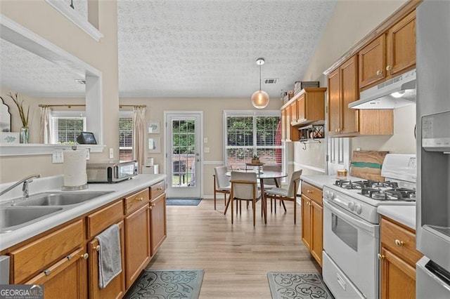 1865 Morgans Run Trl, Buford, GA 30519 - kitchen featuring white range with gas cooktop, under cabinet range hood, a textured ceiling, light countertops, and light wood-style floors