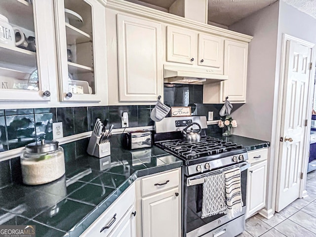 329 Royal Crescent Way, Stockbridge, GA 30281 - kitchen with stainless steel range with gas stovetop, under cabinet range hood, tasteful backsplash, glass insert cabinets, and white cabinetry