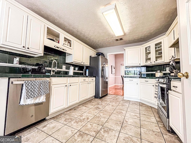 329 Royal Crescent Way, Stockbridge, GA 30281 - kitchen featuring appliances with stainless steel finishes, tasteful backsplash, white cabinetry, glass insert cabinets, and a textured ceiling