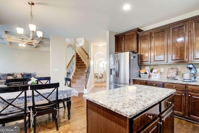 3746 Okefenokee Rdg, Loganville, GA 30052 - kitchen featuring stainless steel refrigerator with ice dispenser, arched walkways, wood finished floors, decorative backsplash, and light stone counters
