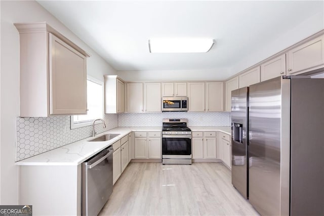 436 Crestmont Ln, Canton, GA 30114 - kitchen featuring appliances with stainless steel finishes, a sink, light wood-type flooring, light stone counters, and decorative backsplash