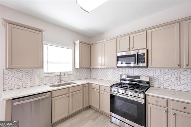 436 Crestmont Ln, Canton, GA 30114 - kitchen featuring appliances with stainless steel finishes, a sink, tasteful backsplash, light wood-style floors, and light stone countertops