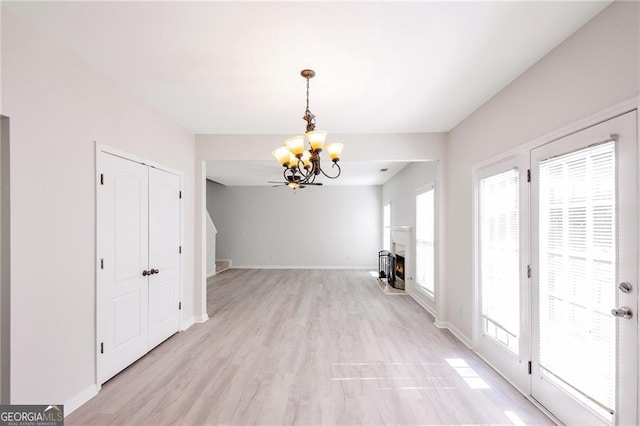 436 Crestmont Ln, Canton, GA 30114 - unfurnished dining area with a chandelier, light wood-style floors, baseboards, and a warm lit fireplace