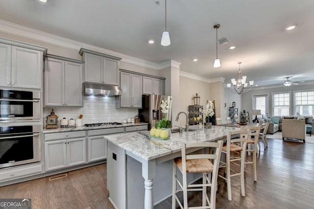 747 Topsail Ln, Alpharetta, GA 30005 - kitchen featuring appliances with stainless steel finishes, gray cabinetry, under cabinet range hood, open floor plan, and a kitchen breakfast bar