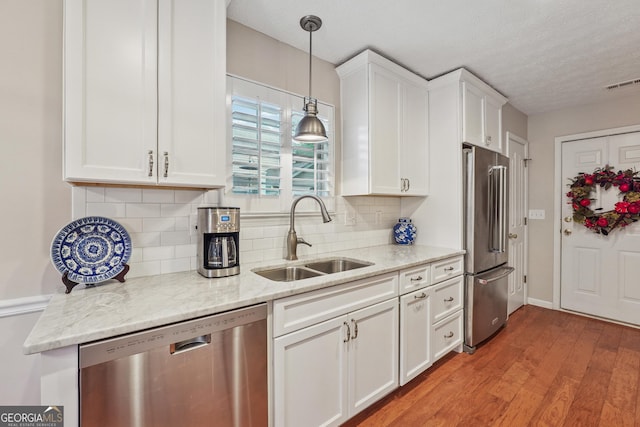 412 Rock Creek Dr, Peachtree City, GA 30269 - kitchen featuring appliances with stainless steel finishes, a sink, white cabinets, tasteful backsplash, and light wood-type flooring