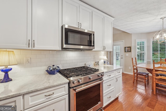 412 Rock Creek Dr, Peachtree City, GA 30269 - kitchen featuring appliances with stainless steel finishes, plenty of natural light, light wood finished floors, white cabinetry, and a textured ceiling