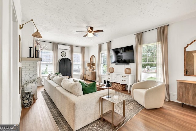 575 E Main St, Buford, GA 30518 - living room featuring a textured ceiling, a ceiling fan, an AC wall unit, wood finished floors, and a fireplace