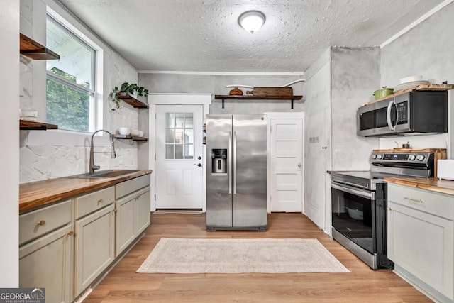 575 E Main St, Buford, GA 30518 - kitchen with stainless steel appliances, open shelves, butcher block countertops, a sink, and a textured ceiling