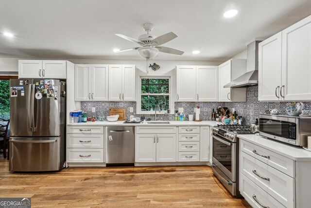 2700 Regency Dr E, Tucker, GA 30084 - kitchen featuring stainless steel appliances, wall chimney range hood, a sink, a ceiling fan, and white cabinetry