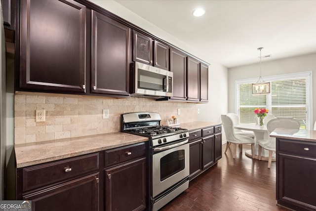 4965 Brierstone Dr, Alpharetta, GA 30004 - kitchen with appliances with stainless steel finishes, tasteful backsplash, dark brown cabinetry, dark wood-type flooring, and hanging light fixtures