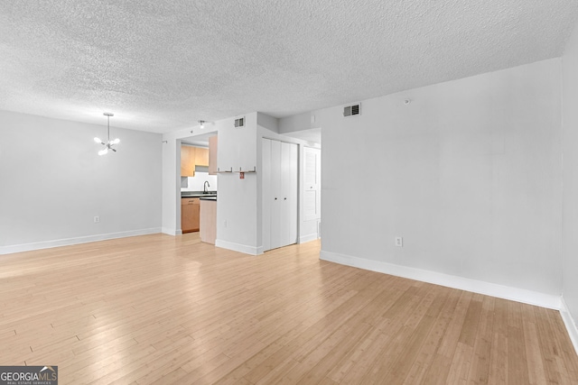 387 Ralph Mcgill Blvd NE Unit K, Atlanta, GA 30312 - unfurnished living room with a chandelier, a textured ceiling, and light wood-type flooring