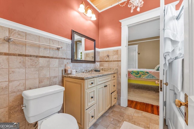403 E Robert Toombs Ave, Washington, GA 30673 - ensuite bathroom with vanity, toilet, tile walls, stone finish floors, and a wainscoted wall