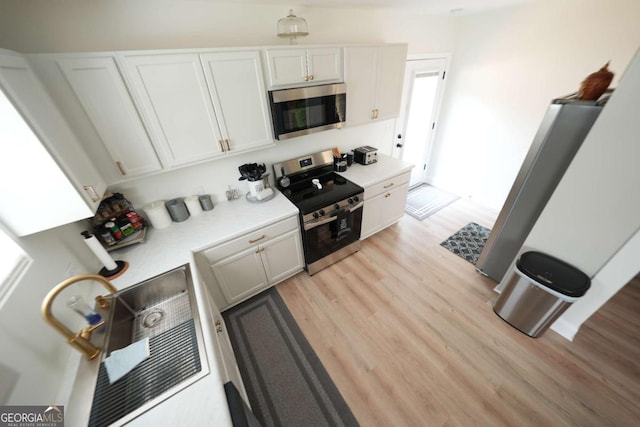 531 Beaver Pond Rd, Carrollton, GA 30117 - kitchen with appliances with stainless steel finishes, light countertops, light wood-style flooring, and white cabinetry