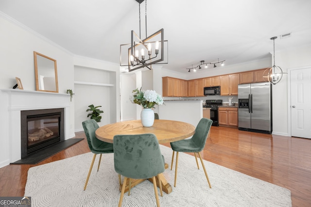 3655 Chattahoochee Summit Dr SE Unit 16, Atlanta, GA 30339 - dining space featuring built in features, crown molding, light wood-type flooring, a chandelier, and a glass covered fireplace
