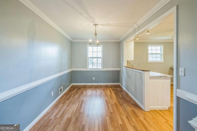 4572 Colonial Rd, Augusta, GA 30907 - unfurnished dining area with plenty of natural light, a chandelier, light wood finished floors, ornamental molding, and a textured ceiling
