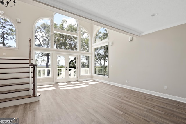 515 Youmans Rd, Midway, GA 31320 - unfurnished living room featuring french doors, a textured ceiling, wood finished floors, stairs, and baseboards