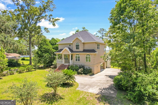 515 Youmans Rd, Midway, GA 31320 - view of front facade featuring concrete driveway, stucco siding, a carport, a front yard, and roof with shingles