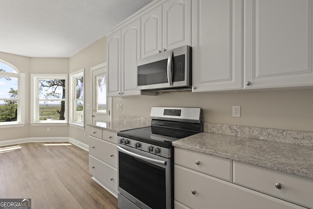 515 Youmans Rd, Midway, GA 31320 - kitchen featuring stainless steel appliances, light wood-style flooring, white cabinets, baseboards, and a textured ceiling