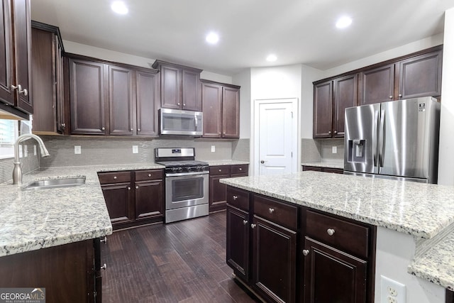 3758 Lake Haven Way, Atlanta, GA 30349 - kitchen with stainless steel appliances, a sink, dark brown cabinets, tasteful backsplash, and a center island