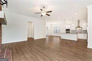 5924 Mitchell St, Flowery Branch, GA 30542 - unfurnished living room featuring a ceiling fan, dark wood finished floors, and a fireplace