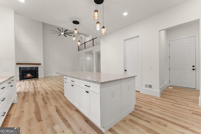 305 Etowah Cove Rd, Dahlonega, GA 30533 - kitchen with light wood-type flooring, white cabinets, hanging light fixtures, light stone counters, and a fireplace